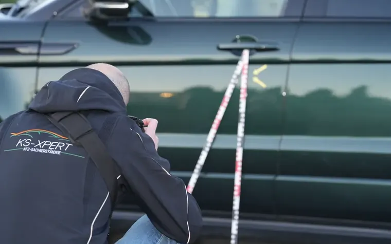 Sachverständiger misst einen Türschaden mit dem Maßstab nach und fotografiert ihn